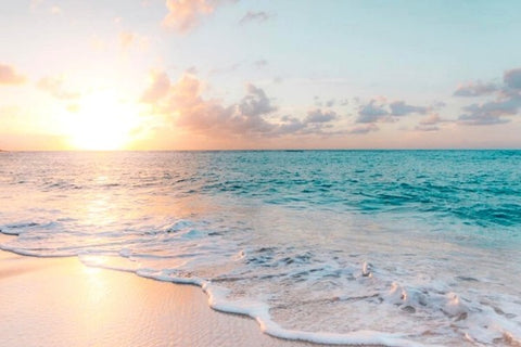 Sunrise over an aquamarine ocean and white sand beach.