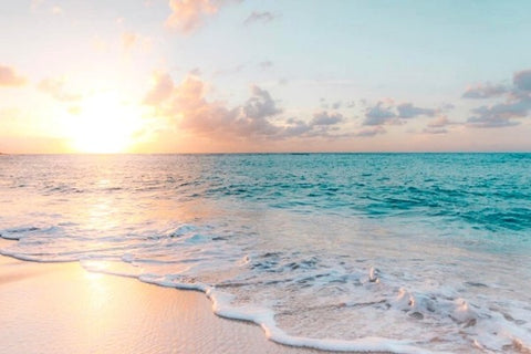 Sunrise over an aquamarine ocean and white sand beach. 