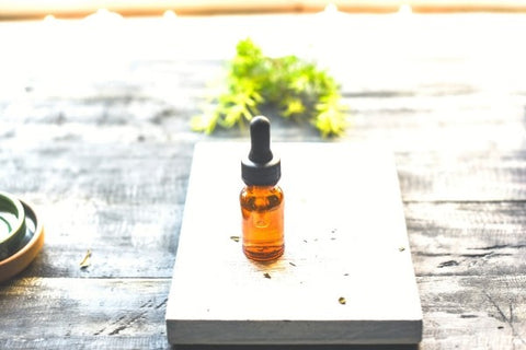 Lavender essential oil in corked glass bottle, in front of lavender plant.
