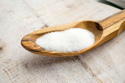 Aspartame on a wooden spoon, set atop a wooden table.